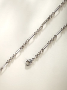 Close-up of silver chain link necklace with lobster clasp in industrial minimalist style