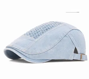 Detail of light blue denim flat cap showing brass buckle and reinforced stitching texture