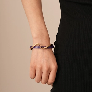 Detail of gold plated double-layer open bangle with purple shell inlay on female wrist