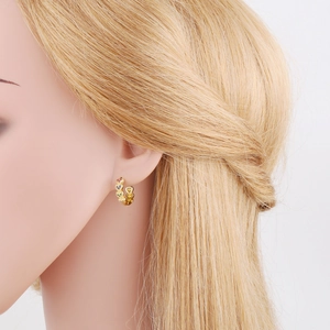 Boucles d'oreilles cœur dorées avec zircons colorés présentées de profil sur modèle