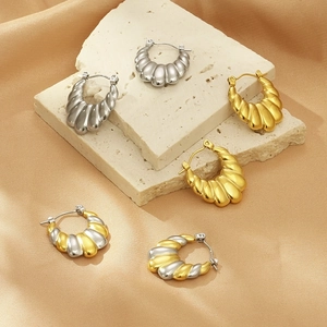 Gros plan de boucles d'oreilles créoles U nervurées en or et argent sur pierre