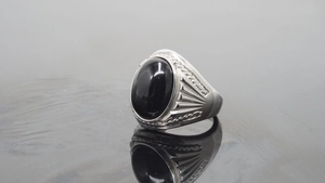 Detail of silver titanium ring with oval black gemstone and vintage engraved side texture
