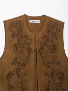 Detailed embroidery on a brown faux suede vest with ethnic patterns and neck tag