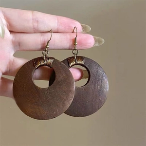 Detail of vintage round brown wooden earrings with golden wire wrapping and silver needles