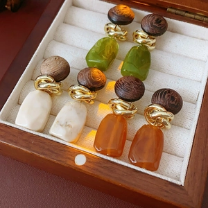 Detailed close-up of vintage geometric resin and wood earrings in ivory, amber, and green