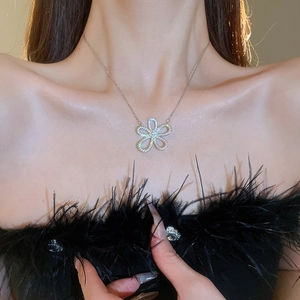 Close-up of sparkling floral pendant necklace worn by model featuring silver petals
