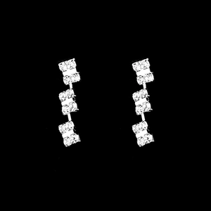 Close-up of silver drop earrings with three square-shaped glittering zircon crystals