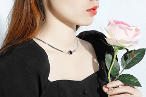 Close-up of a silver-toned flat snake chain necklace with a black round shell pendant