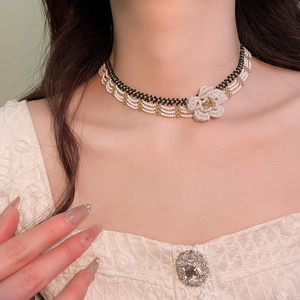 Detail of beaded floral choker with cream and gold beads on an elegant model neck