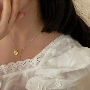 Detail of a gold heart pendant necklace with zircon stone worn on a model's neck