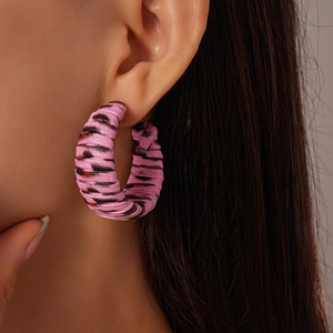 Macro detail of pink leopard print C-shape earrings with leather wrap texture