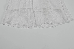 Detailed close-up of white floral lace fabric with intricate cutout patterns and layered mesh