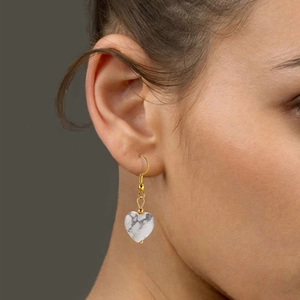 Natural white stone heart-shaped drop earrings with gold hooks on a model