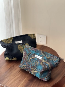 Macro shot of jacquard makeup bags with gold butterfly embroidery and paisley patterns