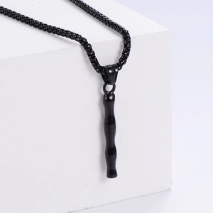 Détail du pendentif noir mat style bambou avec chaîne sur support géométrique blanc