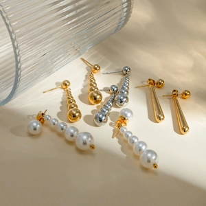 Selection of 18k gold and silver stainless steel earrings with pearls on beige background