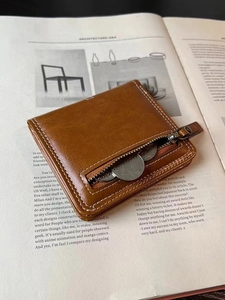 Detail of brown leather coin purse with white stitching and zipper pocket on a book