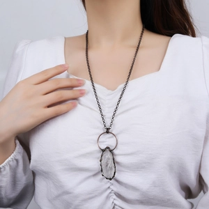 Collana vintage in bronzo con pendente in cristallo bianco naturale su abito bianco
