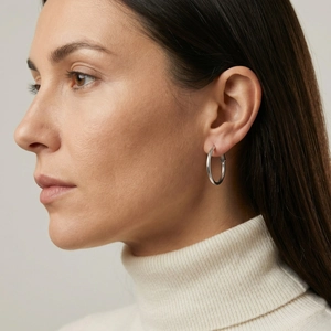 Close-up of minimalist silver hoop earrings worn by a model in high-quality detail