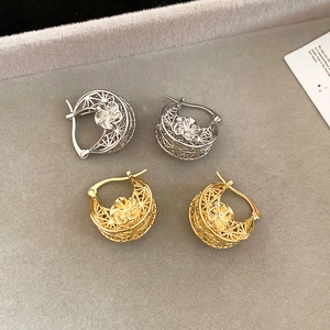 Detailed view of hollow geometric earrings with gold and silver 3D flower centers