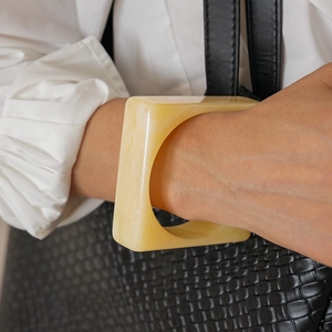 Detailed close-up of chunky square acrylic resin bangle with cream marble pattern