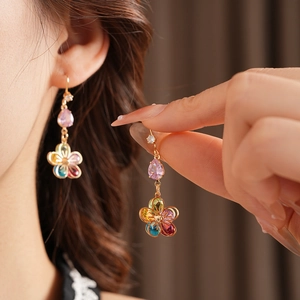 Detail of gold flower earrings with multicolor zircon petals and pink drop pendants