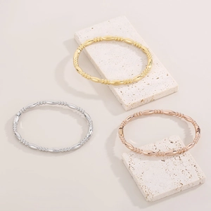 Polished bamboo joint bracelets in gold, silver and rose gold on marble stone display