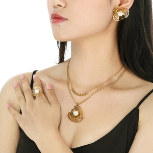 Detailed view of luxury gold steel jewelry set with pearls and hollow shell design