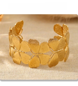 Macro detail showing delicate butterfly wing textures on an 18k gold plated open cuff bracelet