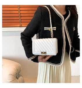 Detail of white quilted leather crossbody bag featuring gold chain and turn-lock closure