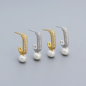 Detail of gold and silver J-shaped earrings with micro-inlaid diamonds and white pearls