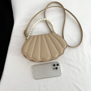 Detail of khaki shell bag featuring vertical stitching and elegant pearl handle chain