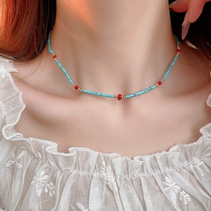 Close-up of Bohemian beaded necklace with blue turquoise tubes and red round beads