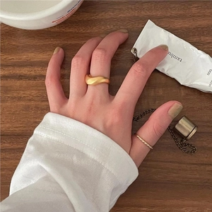 Detailed view of gold twisted rope and wavy stackable rings worn on a model hand