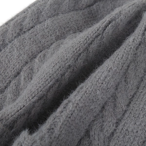 Gros plan sur un tricot gris épais avec texture pelucheuse douce et motif torsadé