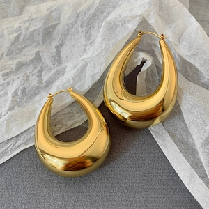 Polished gold teardrop hoop earrings for women on elegant neutral textured background