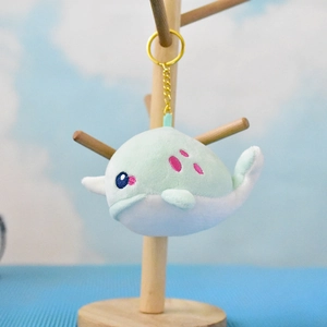 Cute mint green plush narwhal keychain hanging on a wooden stand for bag charm accessory