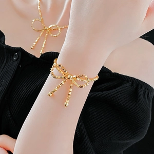 Close-up of golden bow-shaped necklace and bracelet set on model with elegant finish