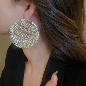 Close-up of oversized silver hoop earrings with shimmering full diamond micro-pave setting