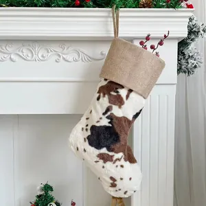 Close-up of cow print plush Christmas stocking hanging on a rustic white fireplace