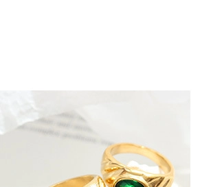 Macro shot of vintage gold ring with green oval gemstone and textured carved band details