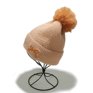Detailed knit texture and orange bow embroidery on thick thermal beige winter beanie hat