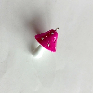 Macro shot of a pink resin mushroom charm with white spots and a metal loop hook