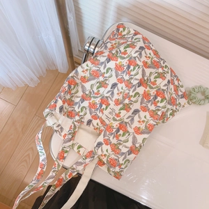 Tragetasche aus Baumwolle mit Blumenmuster und Schultergurten auf weißem Stuhl