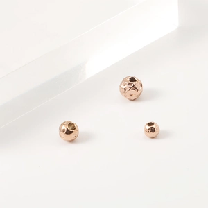 Macro detail of three rose gold hammered finish stainless steel spacer beads for DIY jewelry