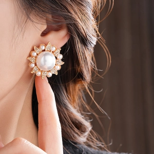Close-up of elegant flower pearl earring with gold metal and sparkling zircons