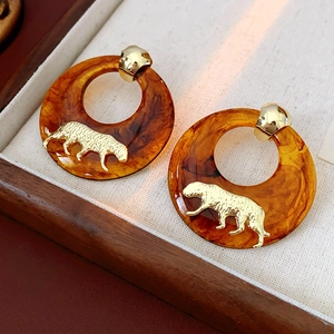 Macro shot of tortoiseshell resin hoop earrings with vintage gold leopard motifs