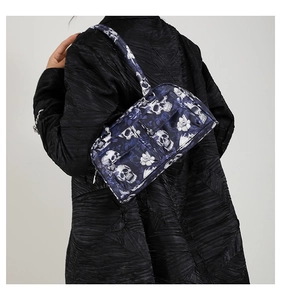 Detailed view of skull and floral print shoulder bag worn with black textured coat