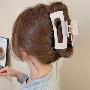 Detailed back view of a large cream white square silicone hair claw clip on a woman's bun