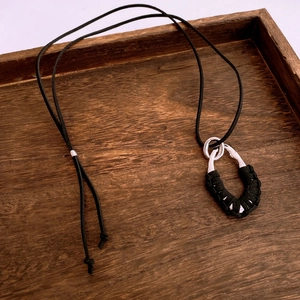 Détail d'un pendentif goutte vintage avec texture tressée noire sur bois rustique